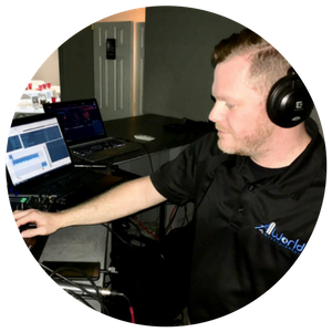 Man wearing headphones working at a desk with a laptop and multiple monitors in a home office