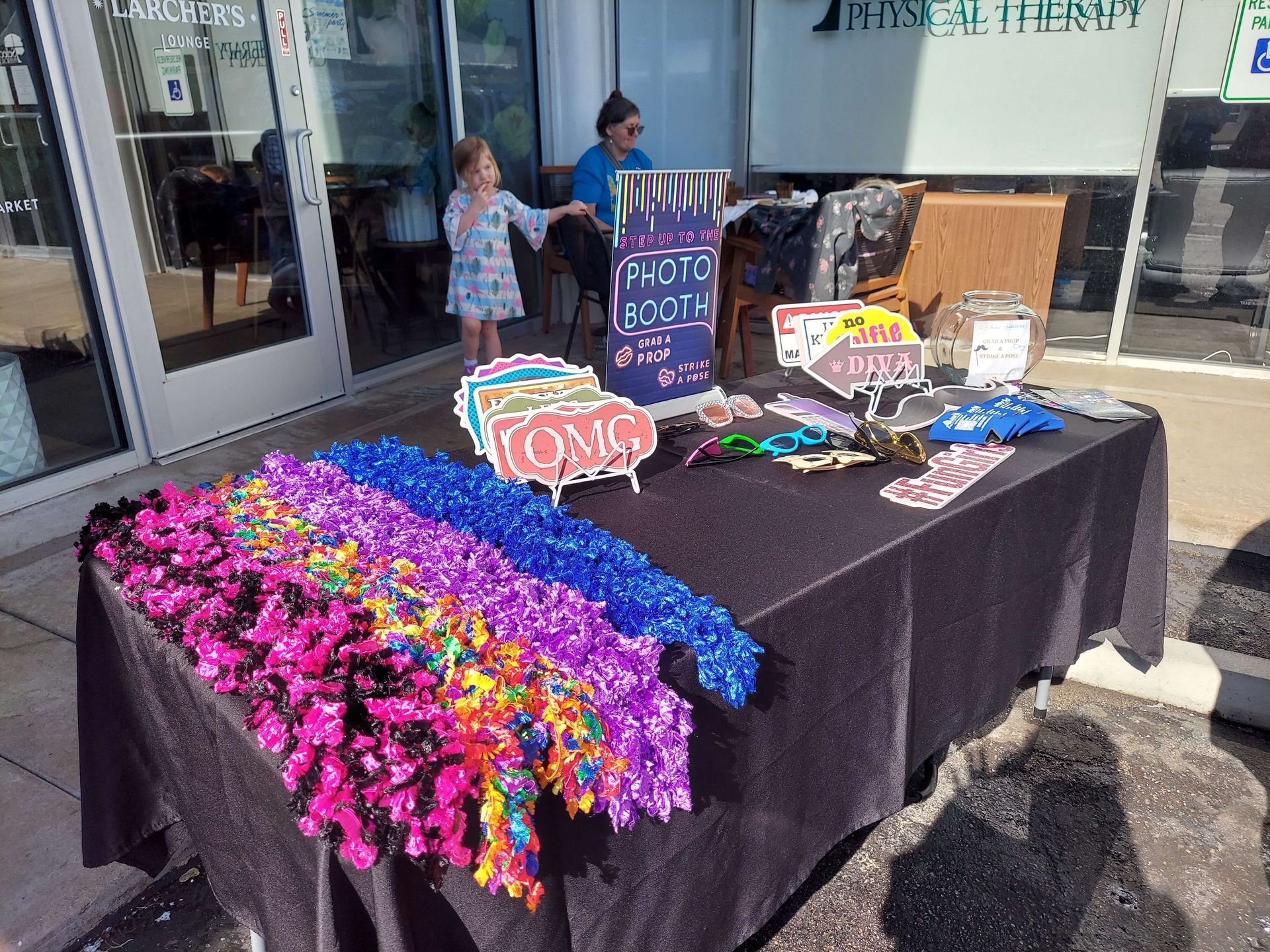 Prop display with colorful leis and T-shirts on a black table outside a storefront