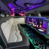 Luxurious limo interior with white and black seating, purple ceiling lights, and neon accents.