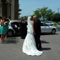 Bride and groom kissing beside a white limo at an outdoor wedding venue