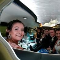 Woman smiles in a limousine with seated passengers behind/beside her