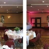 Empty banquet hall with round tables, burgundy chairs, and pink accent lighting on the stage.