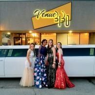 Four women in formal dresses posing in front of a white limousine and Venue 3130 sign