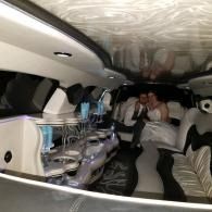 Two people sitting inside a decorated limousine with neon lights and mirrored ceiling