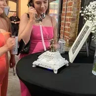 Woman in pink dress viewing a decorative display phone on a table at an event