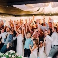 Wedding guests cheering and raising their hands at a lively indoor celebration