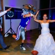 Person in a wolf mask dancing with a woman in a white dress at a party