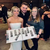 Three people holding a large photo display at an indoor event, smiling at the camera.