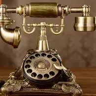 Vintage brass rotary telephone on a wooden table with a separate earpiece and detailed ornate base
