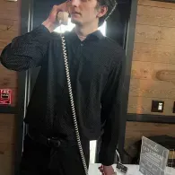 Person in a black shirt using a corded wall phone indoors.