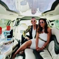 Two people sitting in a white luxury vehicle interior, smiling at the camera