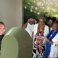 People posing in front of a green photo kiosk with props and lots of smiles