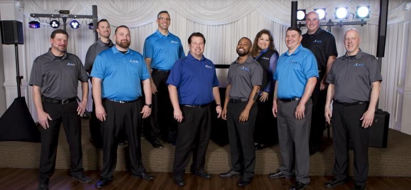 A group of eight people stand in a conference room, posing for a team photo.