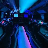 Futuristic limousine interior lit in blue and pink neon, with glowing seats and a central aisle.