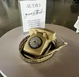 Gold rotary phone on a tray beside an audio guestbook sign on a table