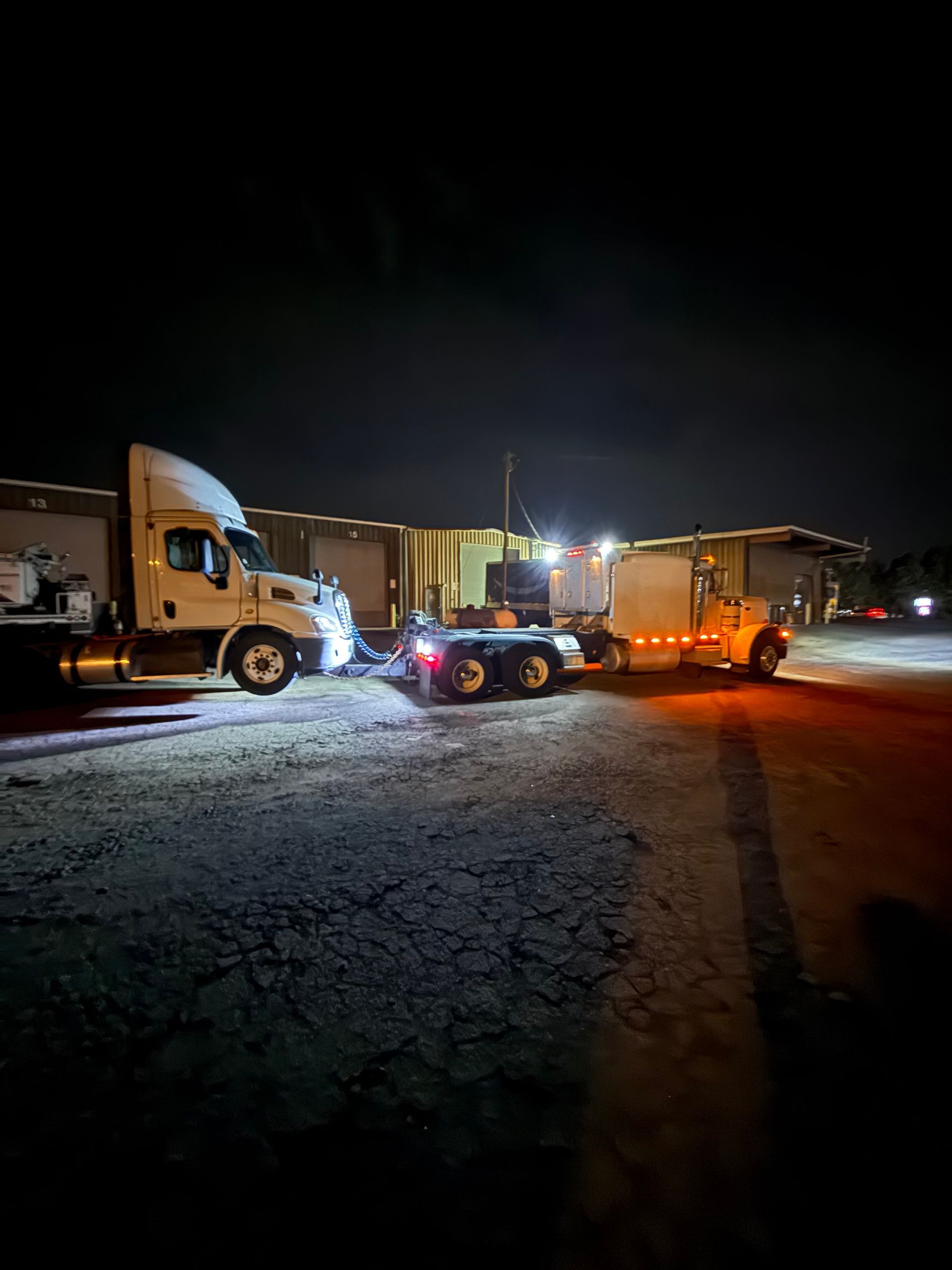 A truck is carrying two tractors down a highway.