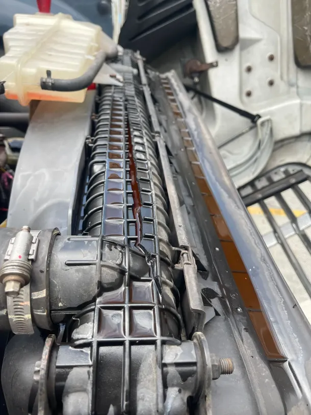 A close up of a radiator on a car with red liquid coming out of it.