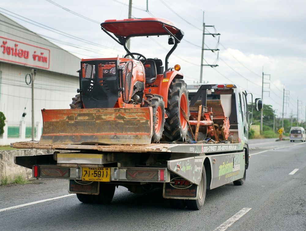 A truck is carrying two tractors down a highway.