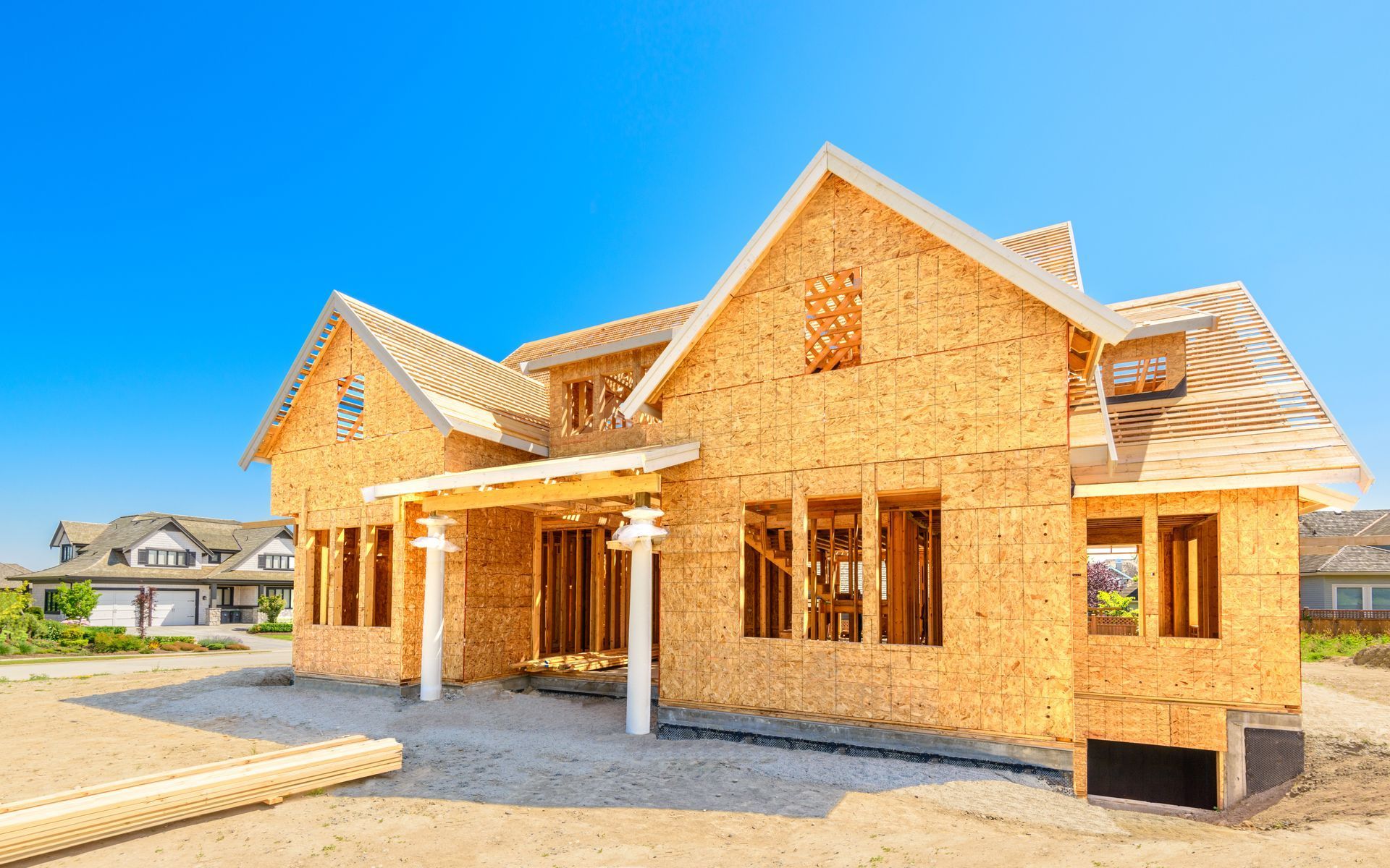 Partially built wooden house under a clear blue sky