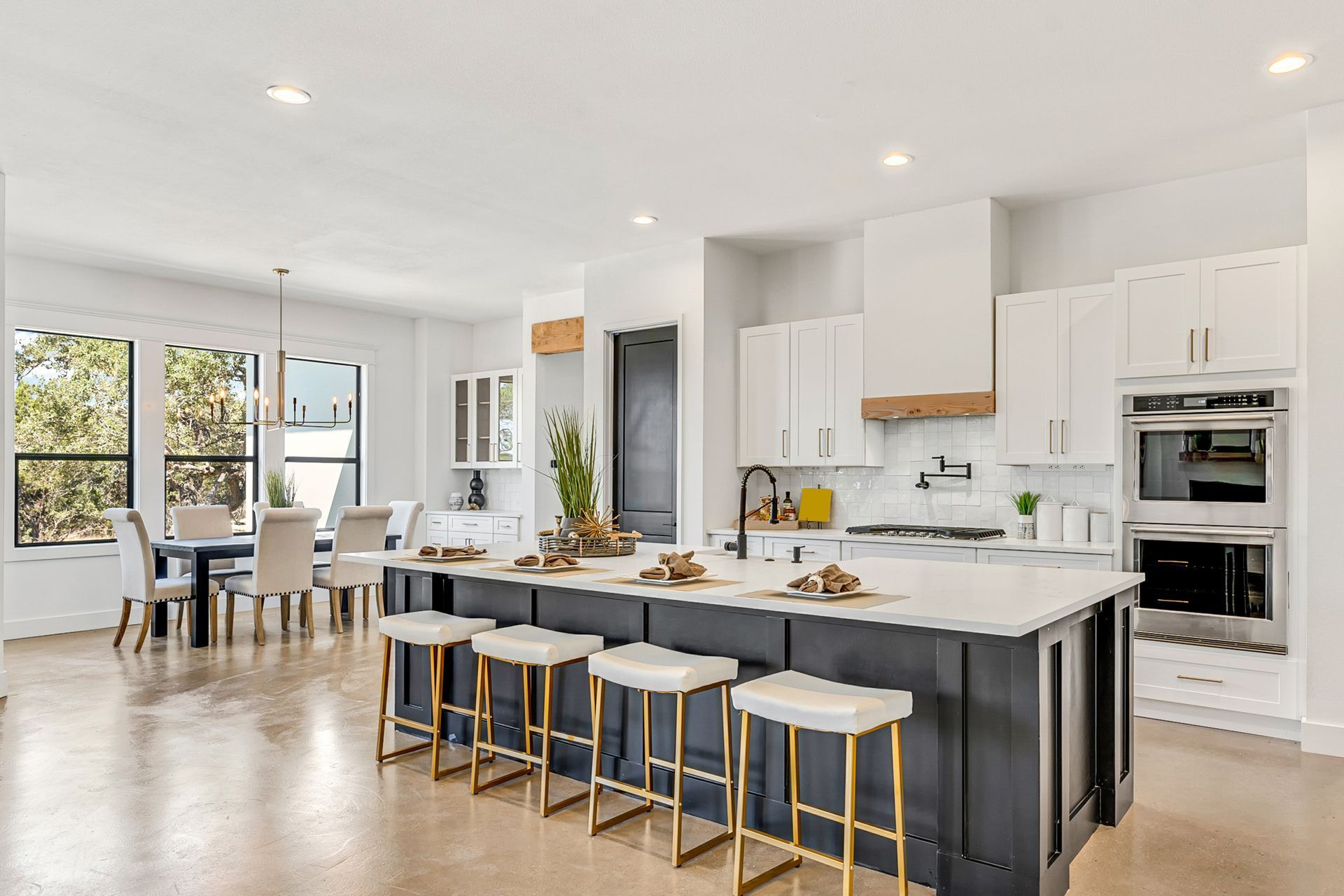 Bright modern kitchen with island seating, white cabinets, and dining area by large windows