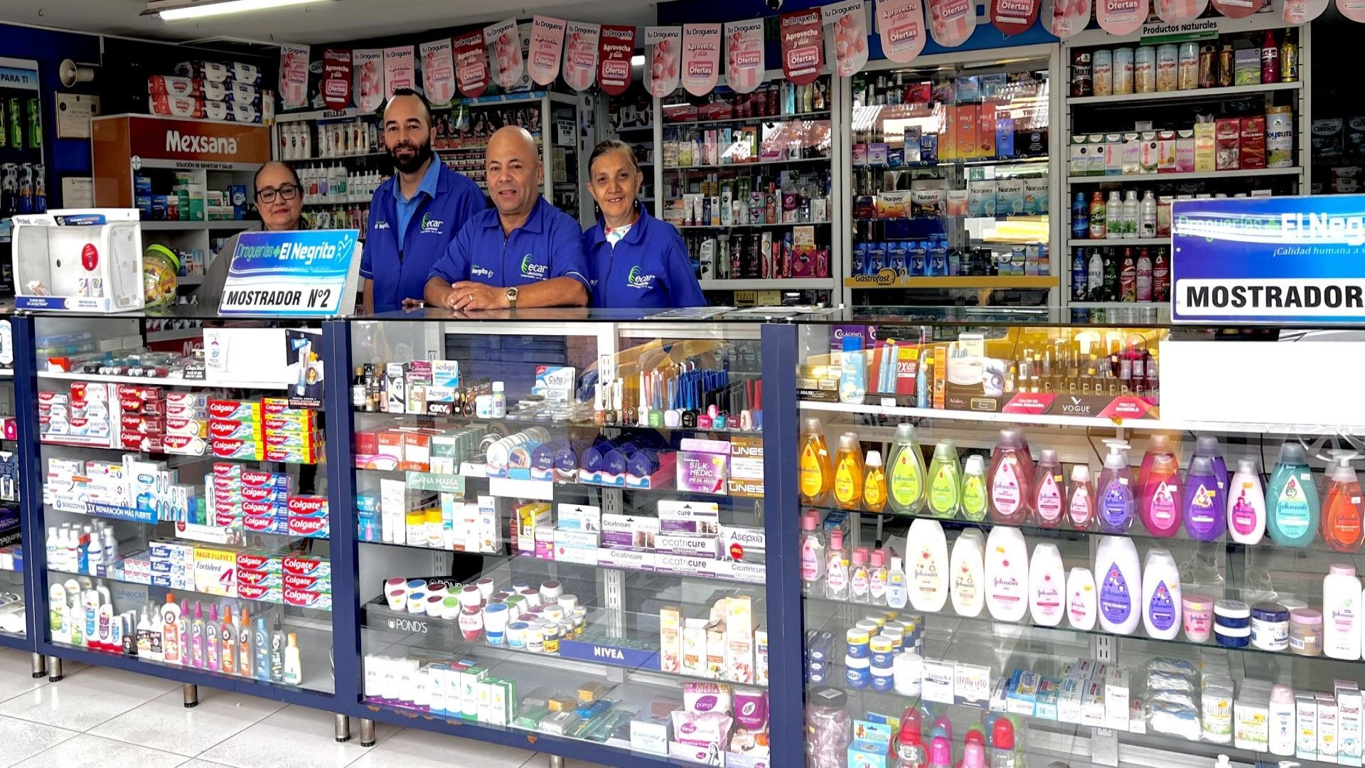 Un grupo de personas se encuentra detrás de un mostrador en una farmacia.