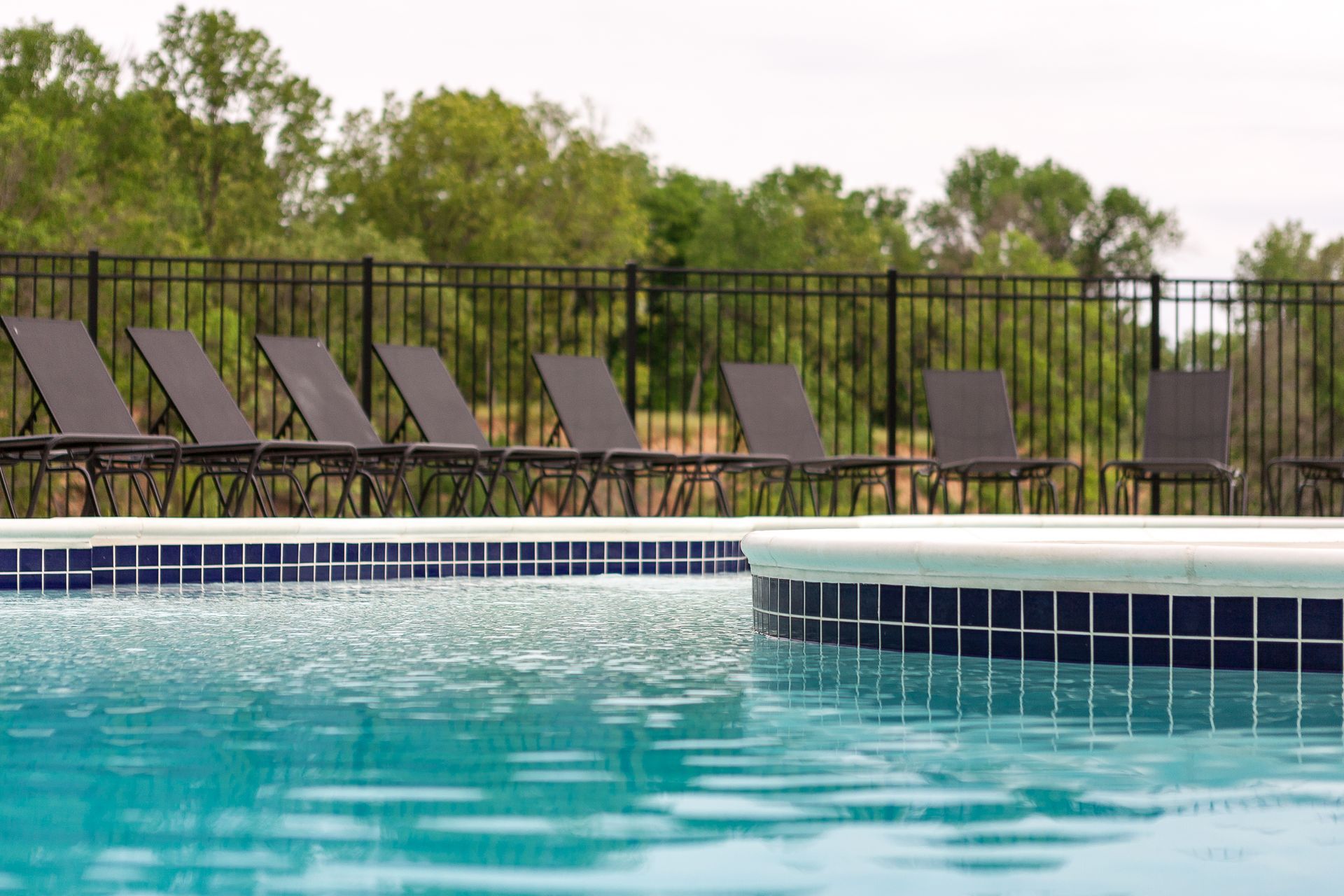 a swimming pool with a fence and chairs around it .