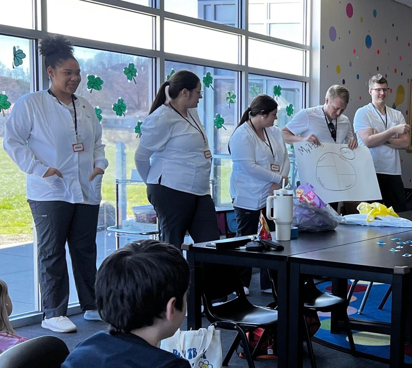 Five Union College nursing students presenting to club kids about healthy habits using a large graph.