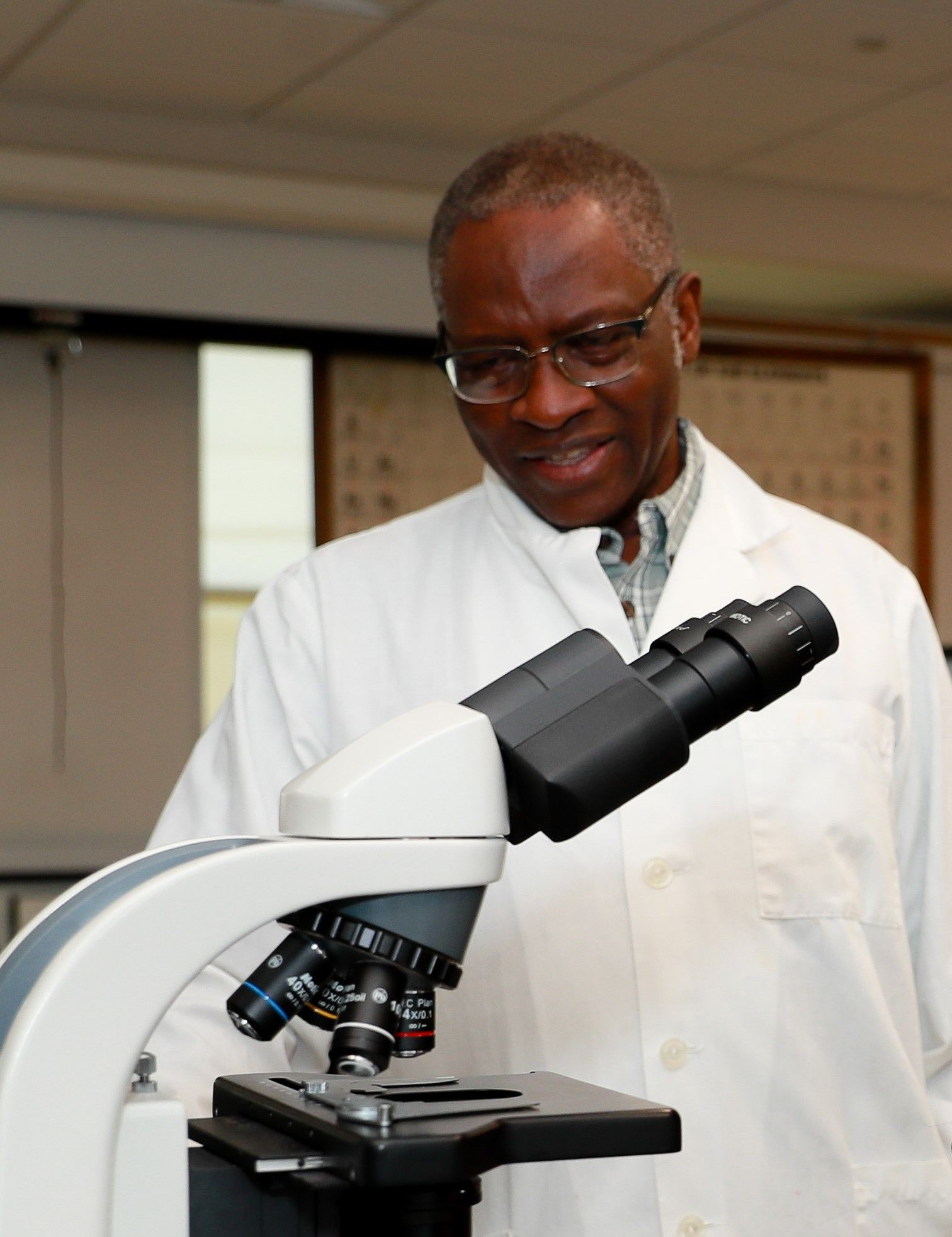 Dr. Fidelis Achenjang standing over a microscope in a lab.