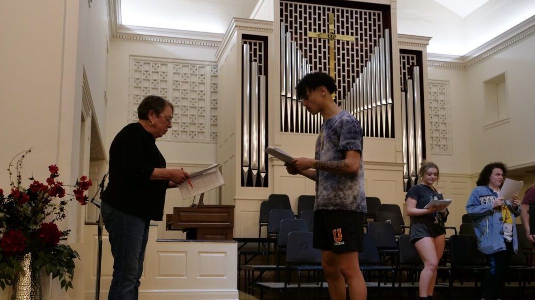 Actors holding scripts rehearsing.