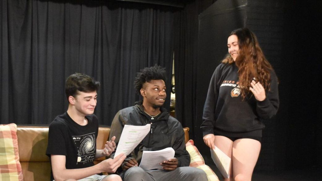 Actors smiling and laughing while they rehearse.