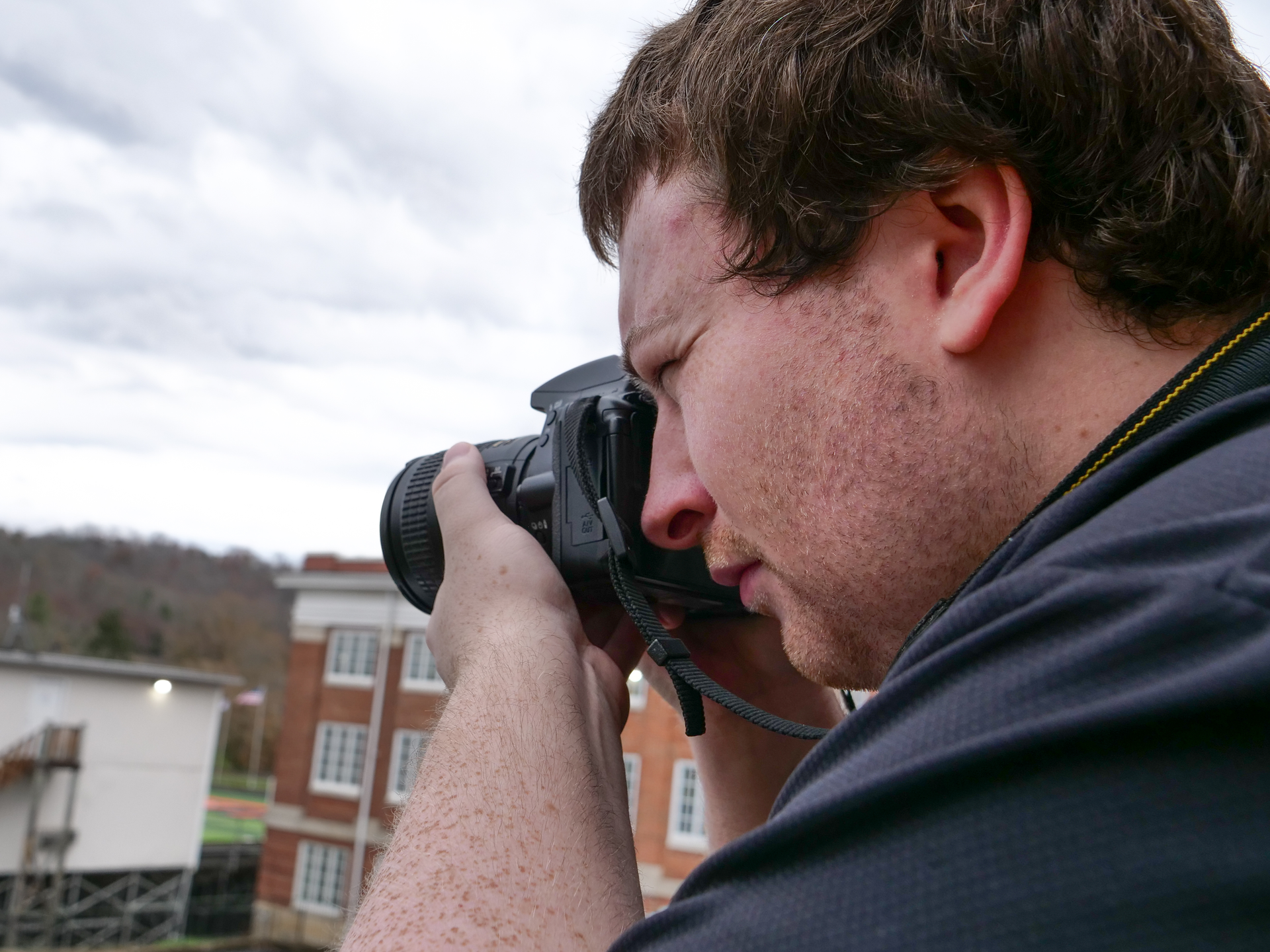 Cody looking through a camera on Union's campus.