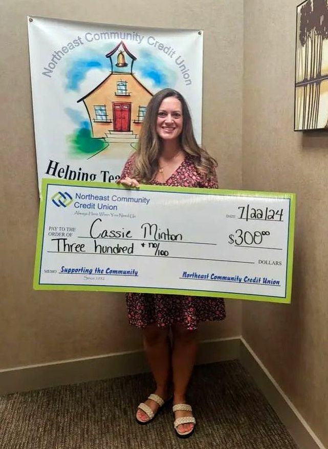 Minton holds a giant check from Northeast Credit Union 