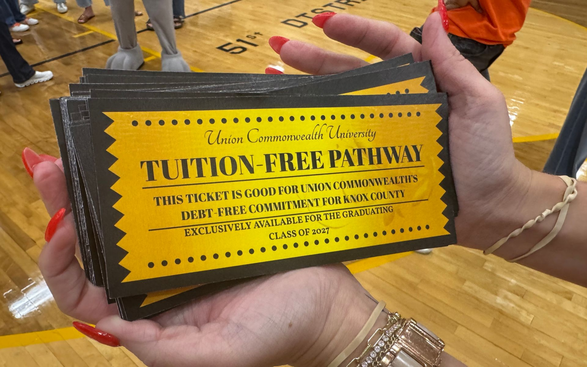 two hands holding a golden ticket that says Tuition Free Pathway