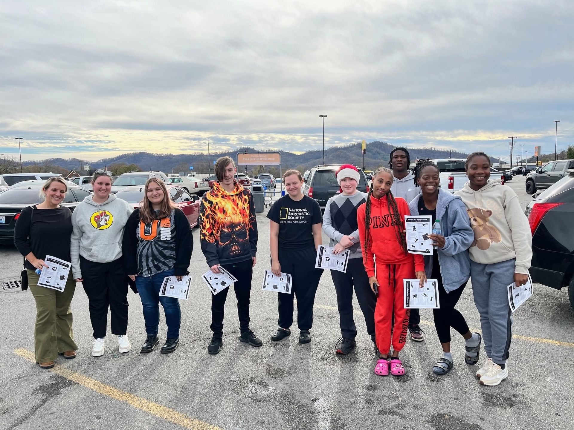 A group of smiling Union students holding shopping lists in a store parking lot.