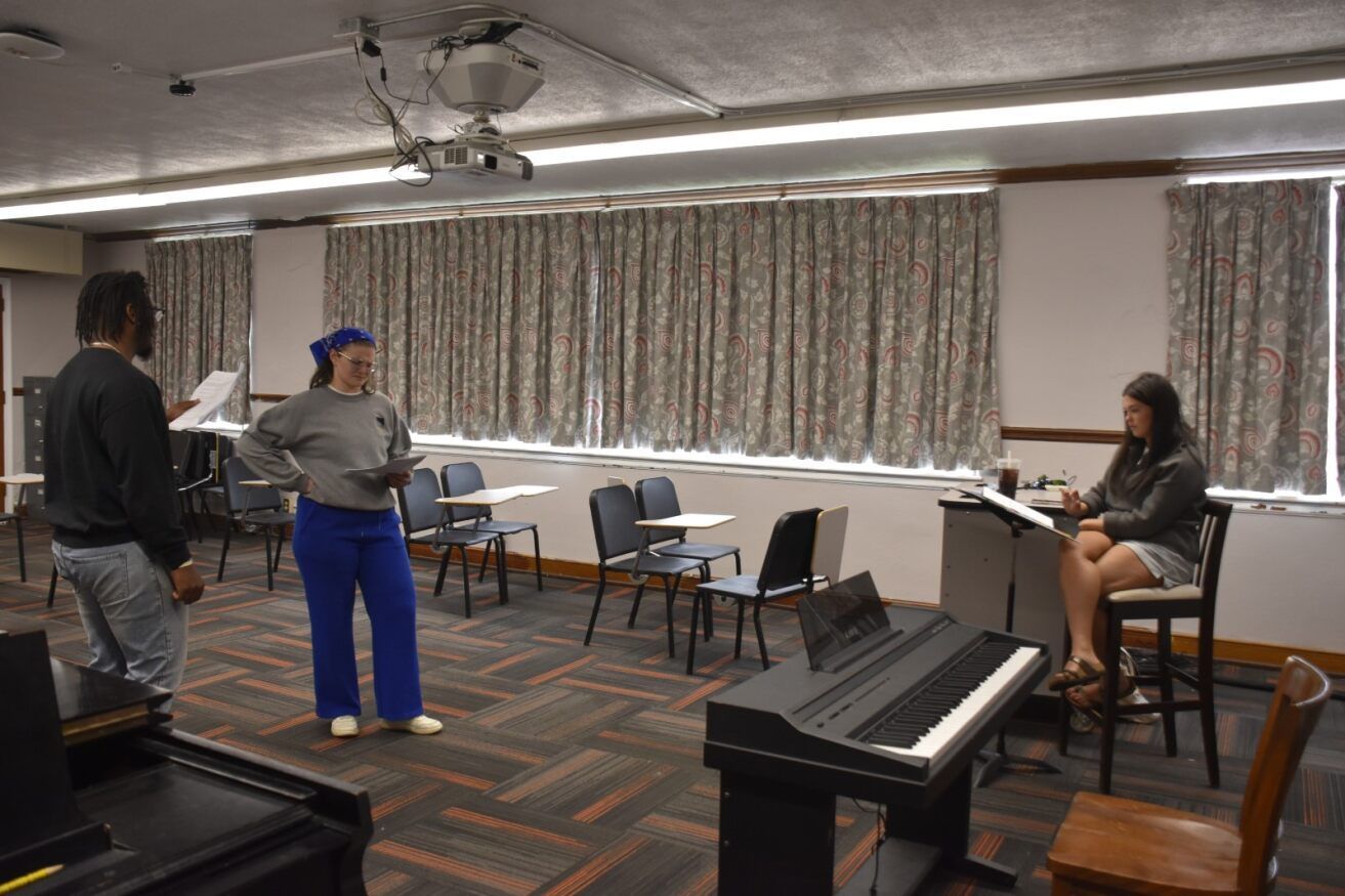 Taryn Mills directing two actors rehearsing.