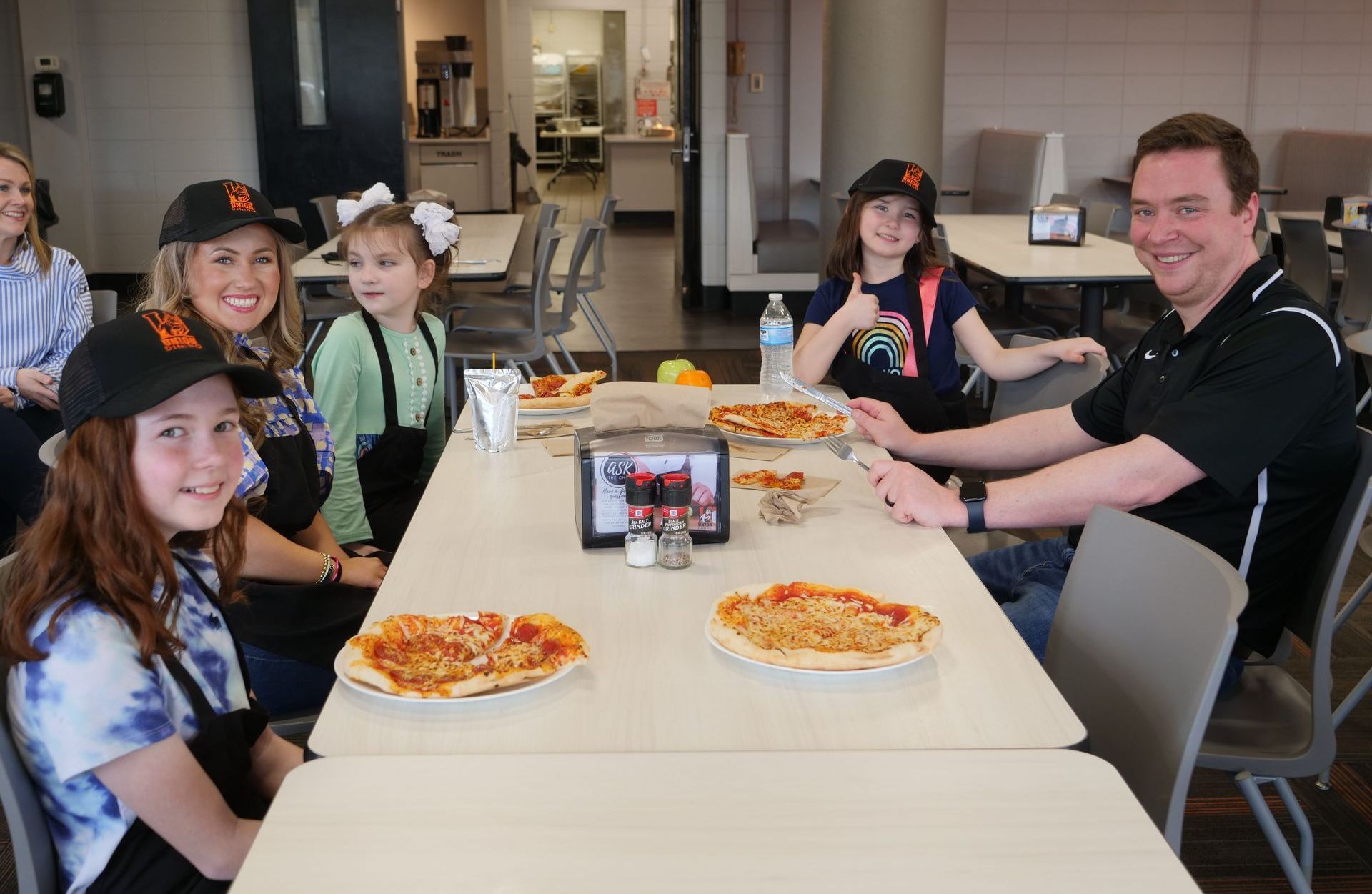 James Becknell and Libby Kate Vaughn sit with child attendees at a table filled with plates of pizza.