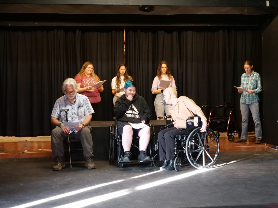 Actors holding scripts rehearsing.
