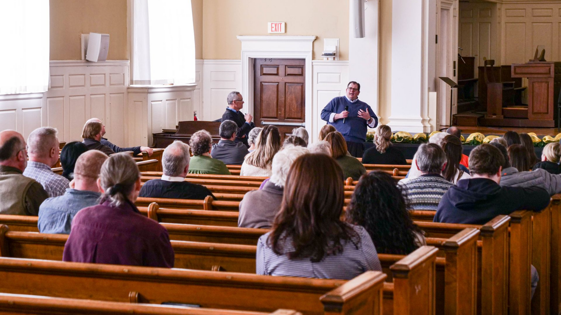 Dr. Bob Helmer and Dr. Joshua Wilkey standing in front of a crowd in the Conway Boatman Chapel.