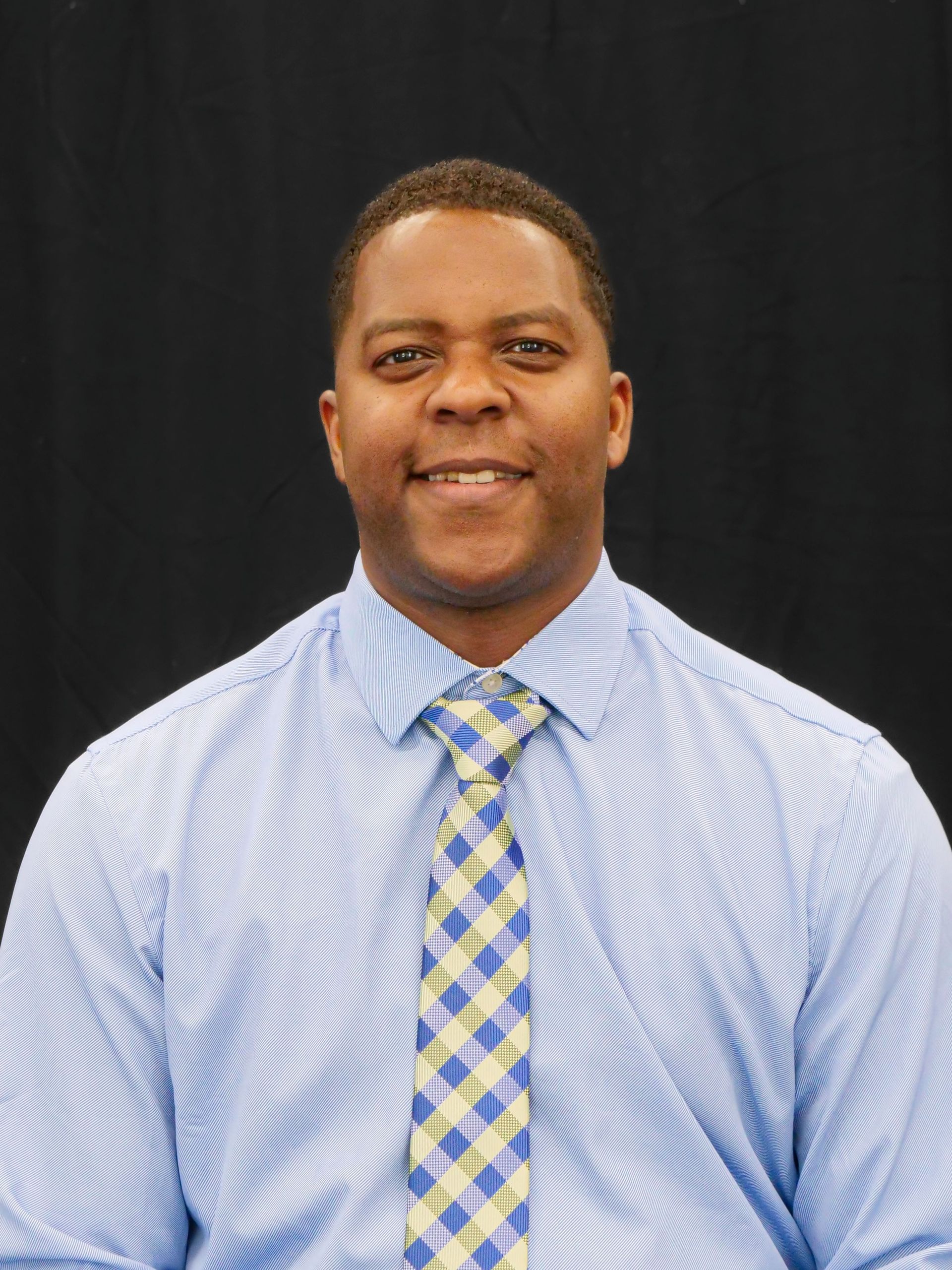 Headshot of President Dr. DJ Washington wearing a light blue shirt and a necktie