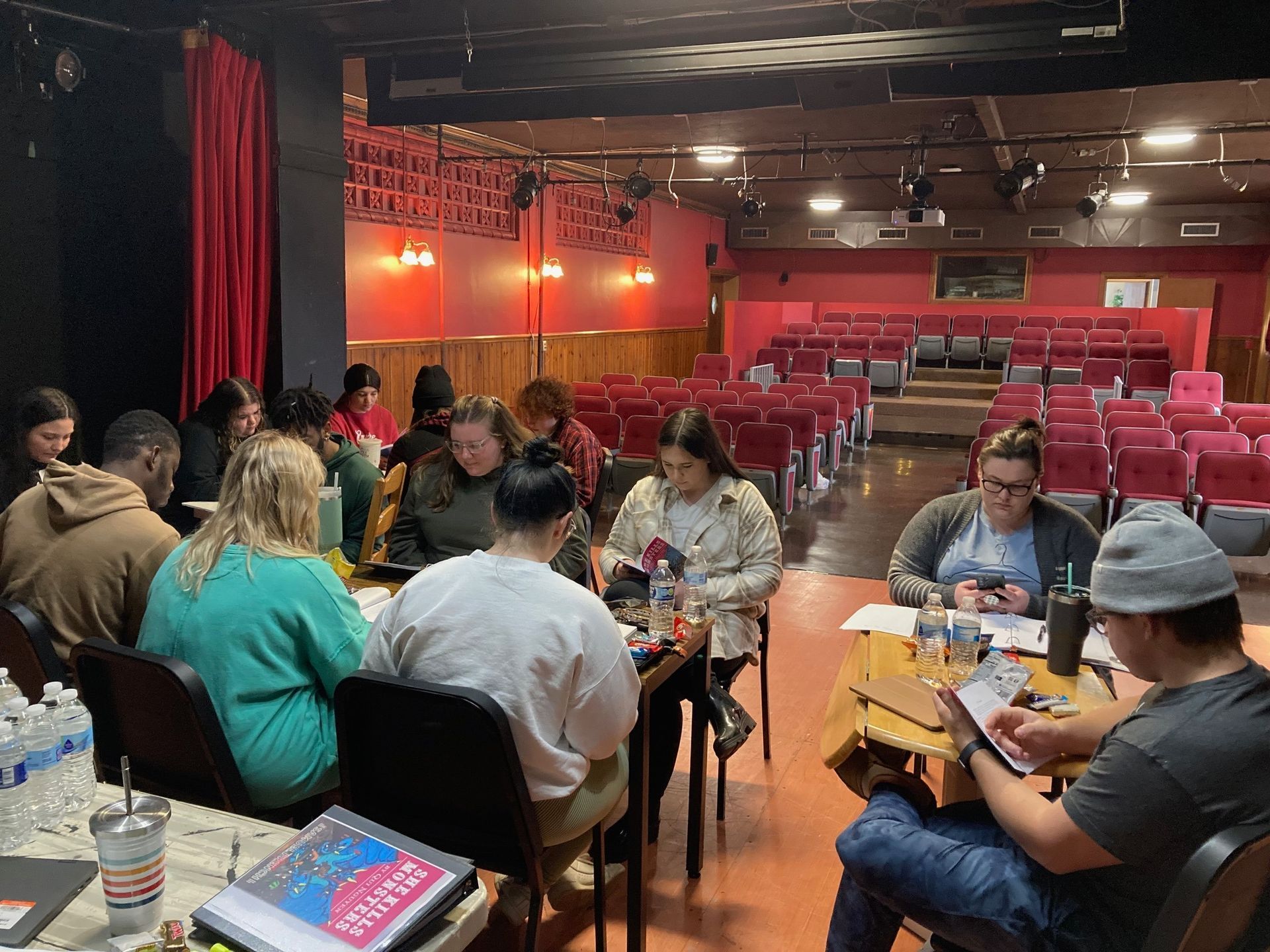 Cast & crew gathered around tables in the Rector Little Theatre doing their first read-through of She Kills Monsters.