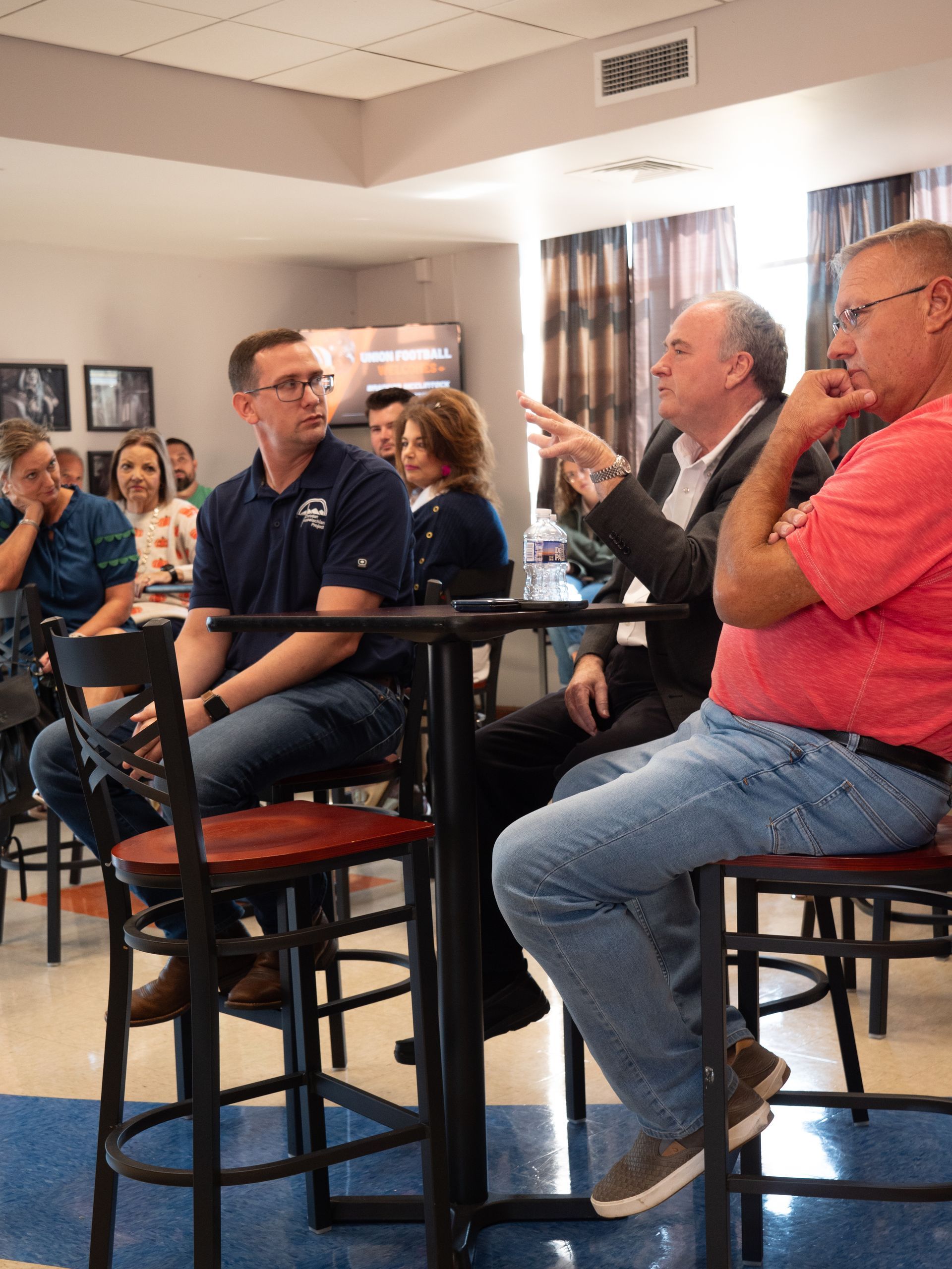 Smith speaks while seated at a small table with other audience members.