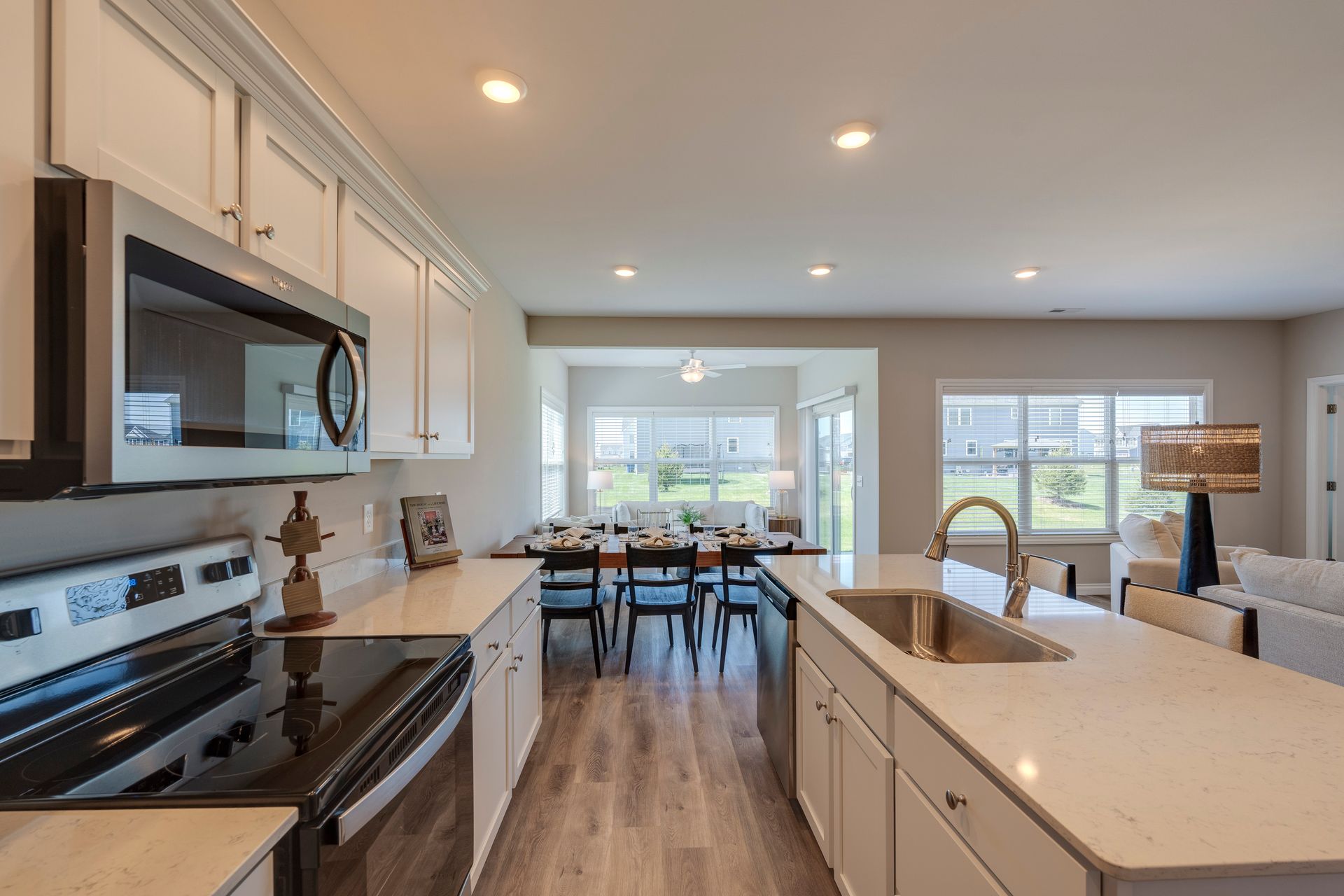 Modern kitchen with white cabinets, stainless steel appliances, and island overlooking dining area.