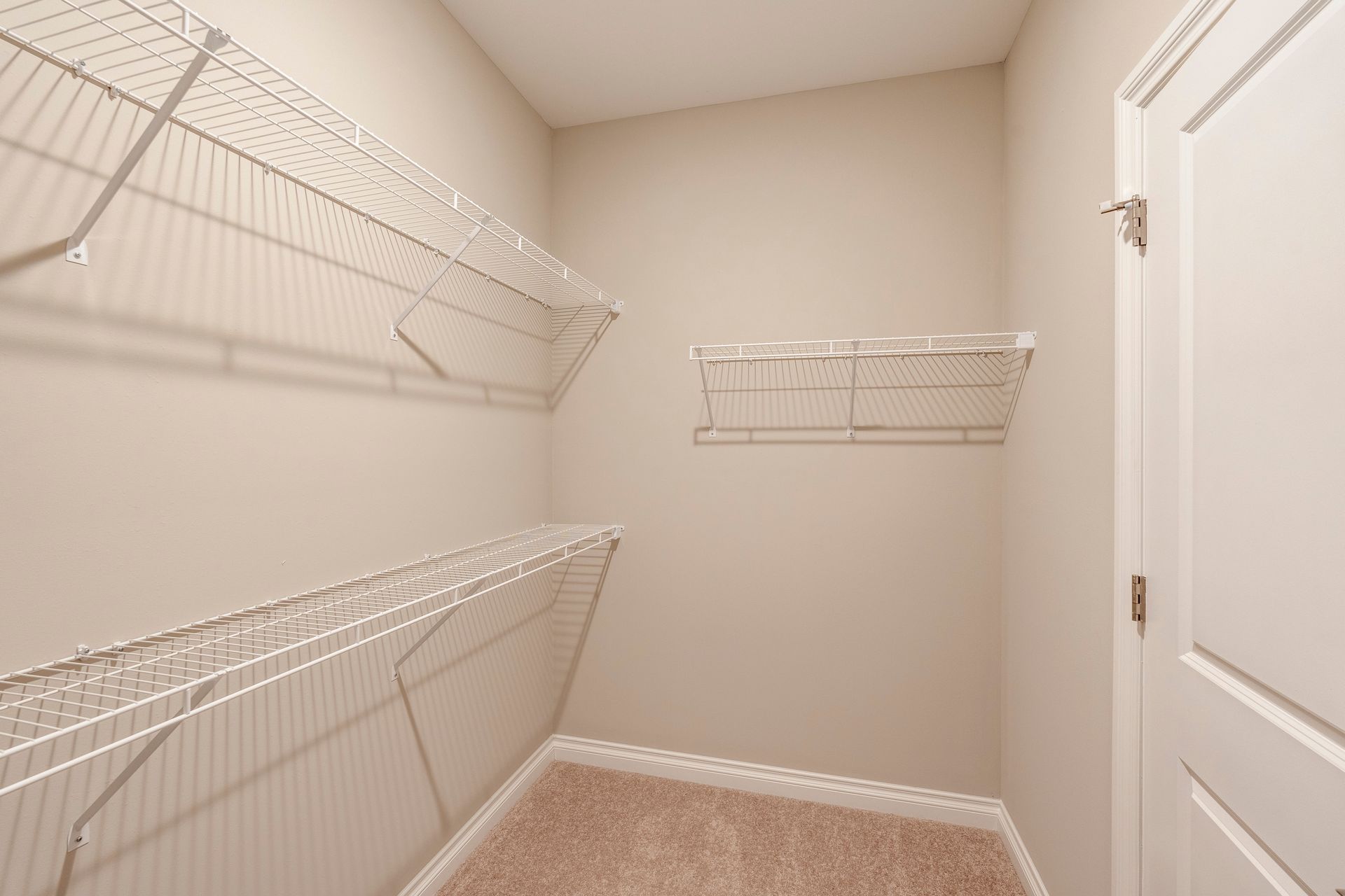 Empty closet with wire shelving and a closed white door.