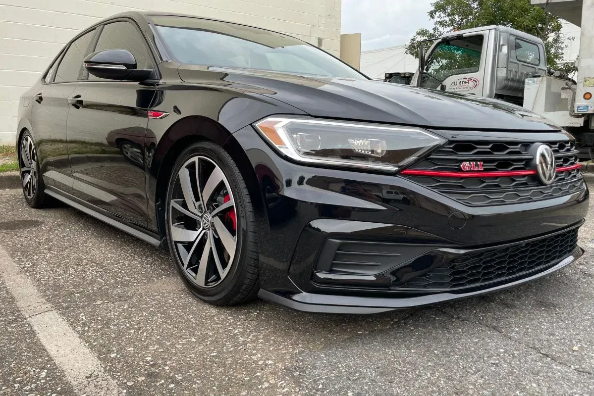 Black Volkswagen Jetta GLI with red accents parked in a lot.