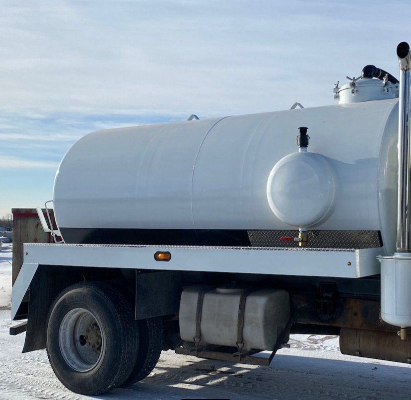 A white tank truck is parked in the snow