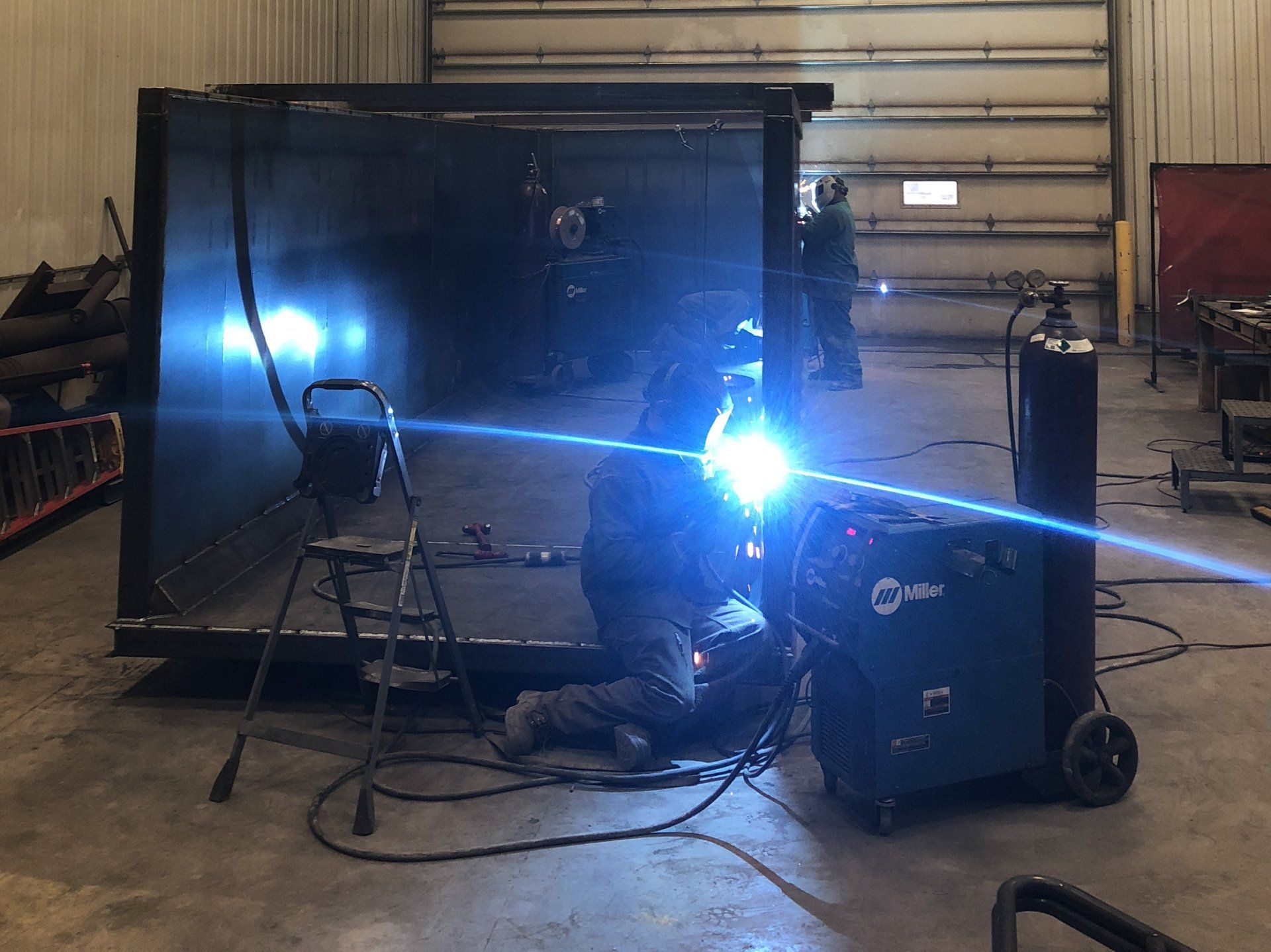 A man is welding a piece of metal in a warehouse.