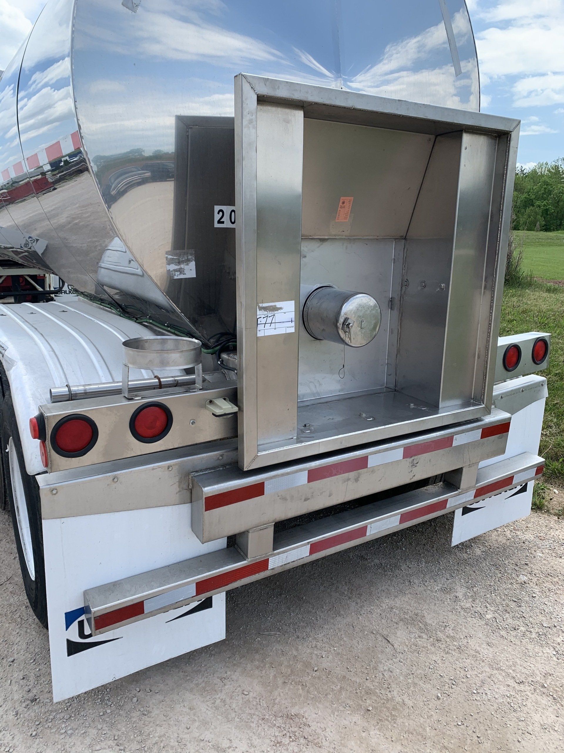 The back of a stainless steel semi truck with the door open.