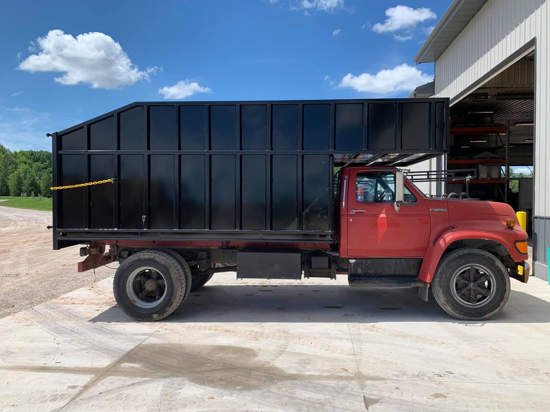 A red dump truck is parked in front of a building.