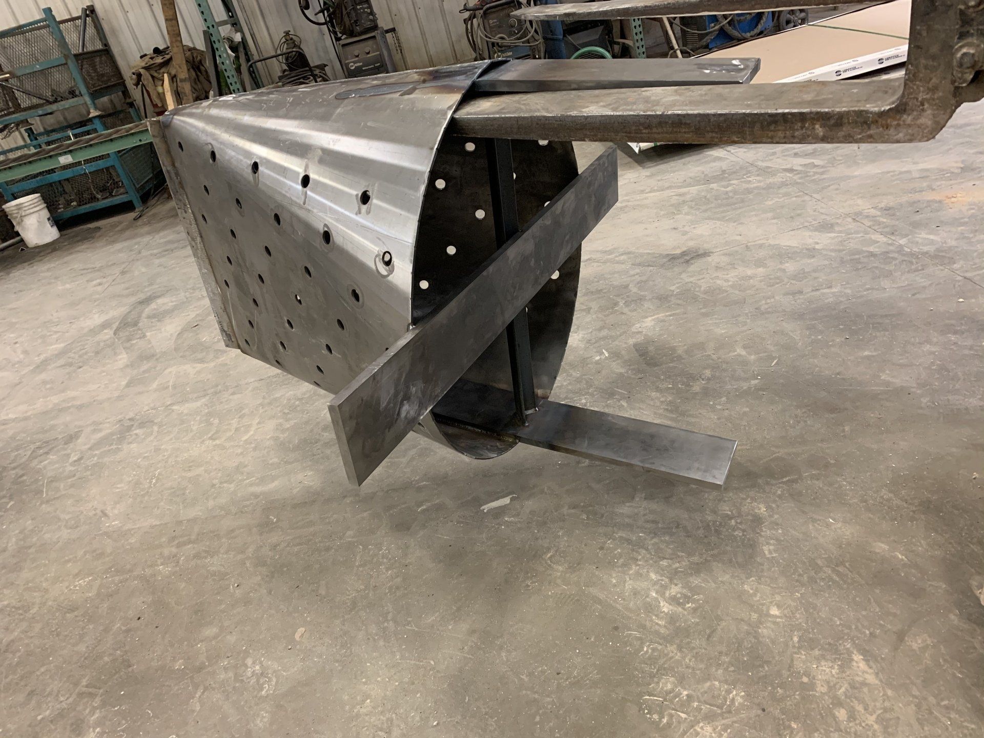 A piece of metal is sitting on a concrete floor next to a forklift.