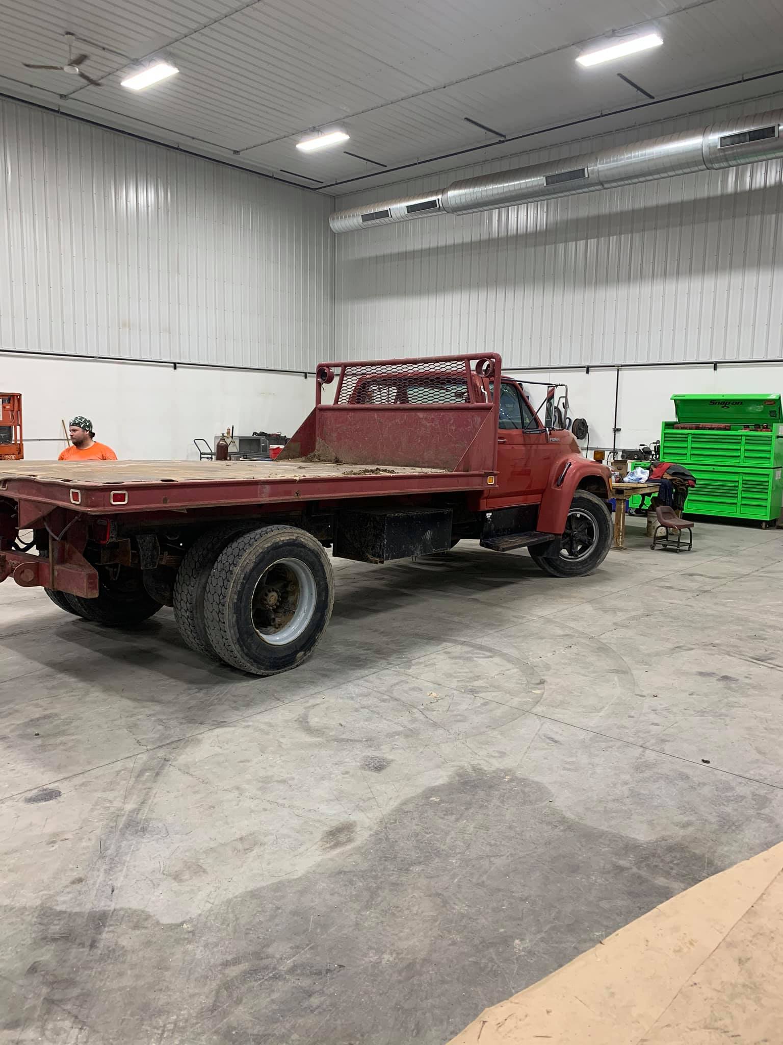 A red flatbed truck is parked in a warehouse.